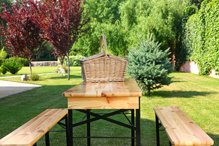 绿色公园木制桌子上的野餐篮子图片