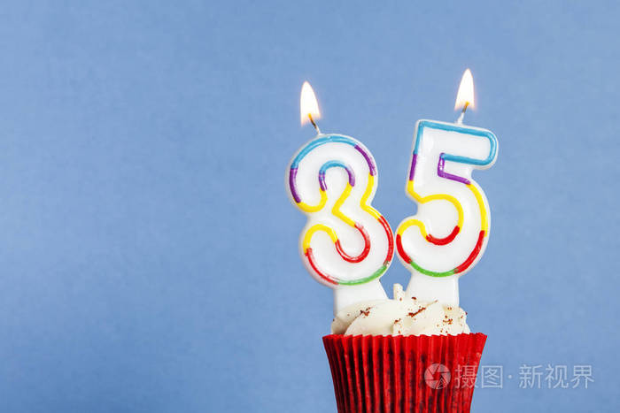 蓝色背景下杯形蛋糕中的35号生日蜡烛