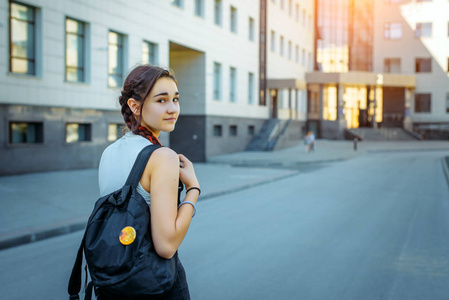 一个年轻漂亮的学生回头看着镜头.一个漂亮的女孩在上学.