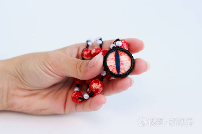 白色背景上一个女孩手上的龙红色眼珠和陶瓷珠护身符