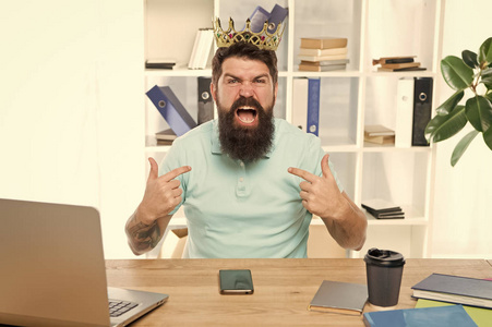 尊重我.男人傲慢无礼,头戴金冠的粗鲁老板坐在办公室里.优越感和自信.