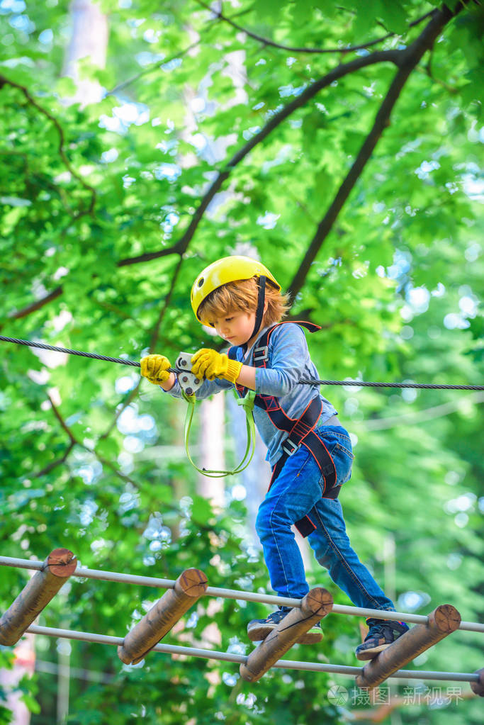 快乐的小男孩一边爬着高高的树和绳子一边叫.孩子们在高绳公园攀爬.