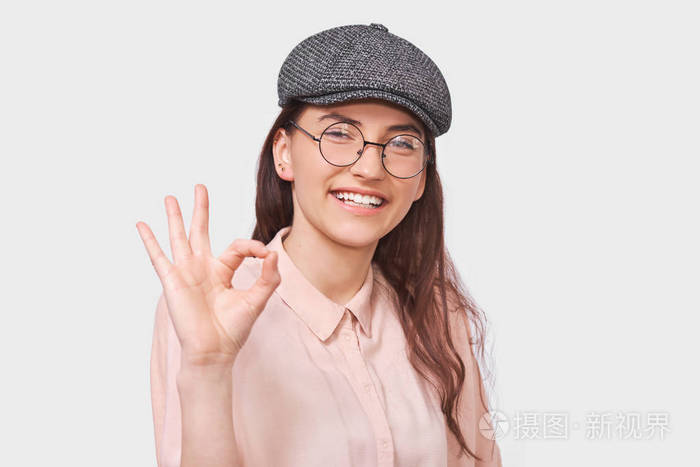 摄影棚正面年轻女性的肖像戴着时髦的灰色帽子粉色衬衫戴着圆圆的透明