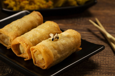 黑盘子里烤蔬菜春卷照片