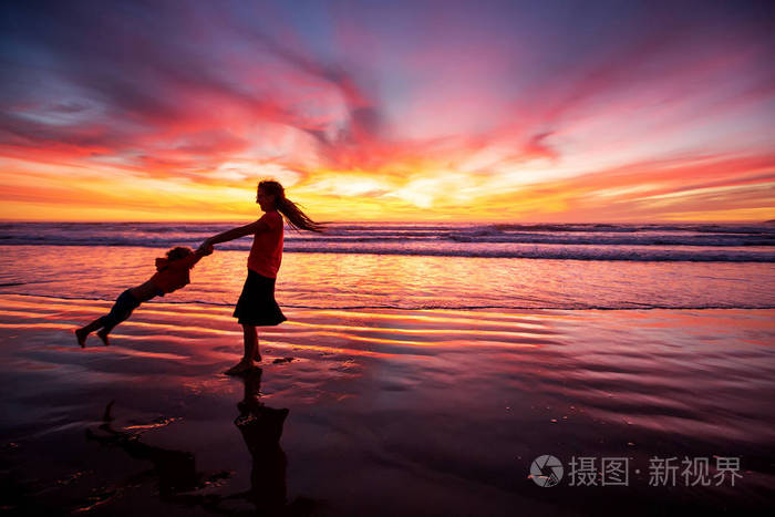 母亲和儿子在海滩上日落时玩得很开心