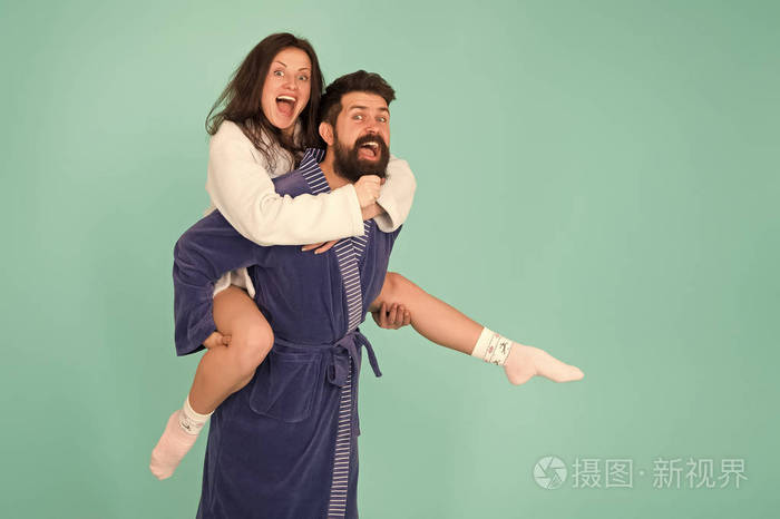 享受在一起的每一秒英俊的年轻人背着漂亮的女人一对穿着浴袍的情侣