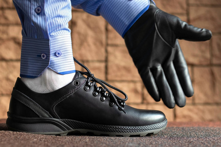 一只戴着黑色皮手套的手指着穿黑色皮靴的脚的方向.