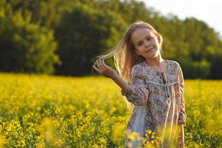 无忧无虑的小女孩在油菜地里欣赏日落.照片