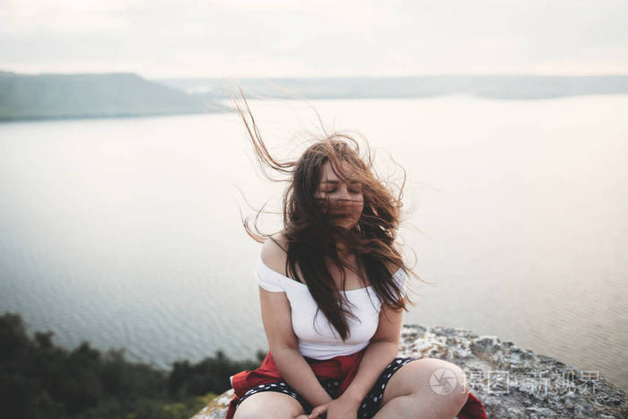 Travel and Meditation. Hipster girl with windy hair sitting and 