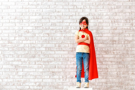 砖墙边扮超级英雄的可爱小女孩图片
