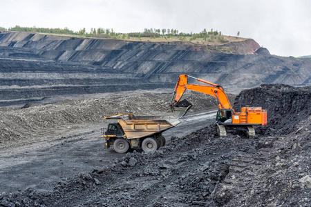 采石场的煤矿开采.液压挖掘机装载自卸车.照片