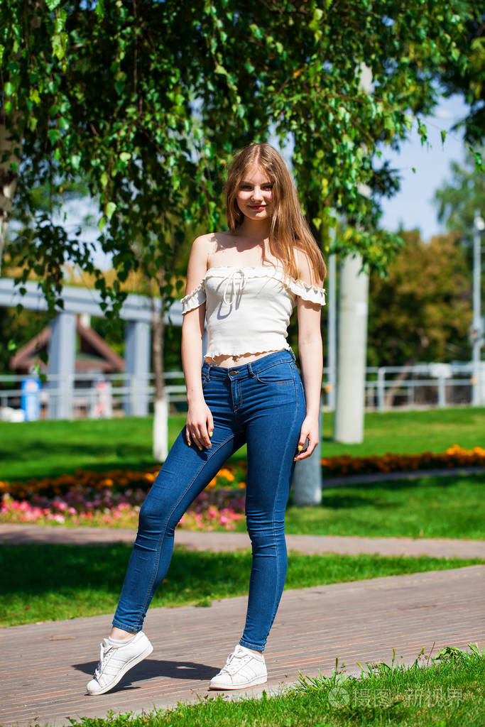 穿着蓝色牛仔裤和白衬衫的年轻金发女商人