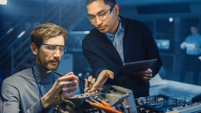 两名专业汽车工程师在一家高科技实验室里用概念车底盘测试一台电动