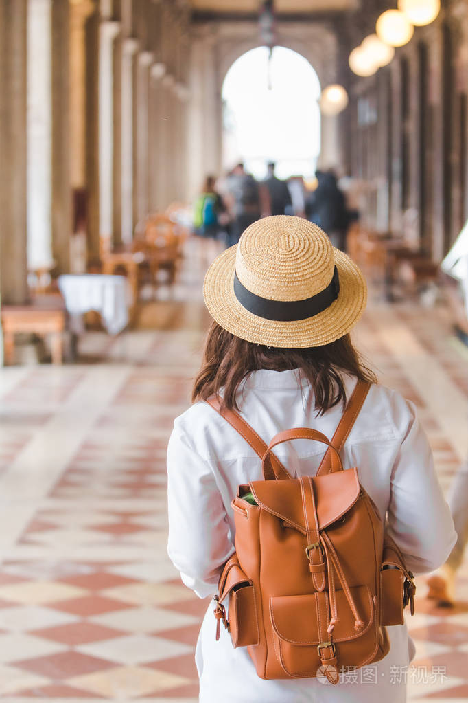 穿着白衣服背着棕黄色背包的女人在户外散步