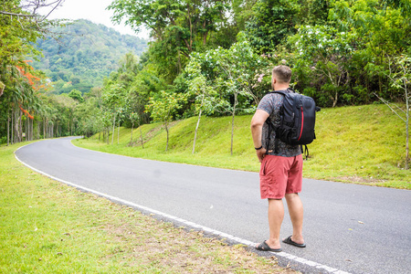 英俊的热带森林和一个旅行者年轻人背着背包走在去泰国森林的路上.