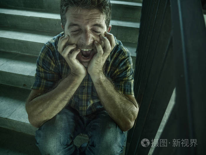 一人坐在黑暗的街道楼梯上,饱受抑郁症和焦虑危机的折磨,尖叫着绝望和