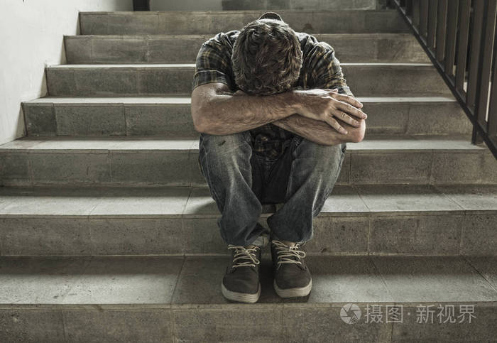 绝望的男人坐在户外黑暗肮脏的街角楼梯上感到不舒服精神健康观念中的