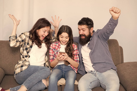 小女孩和爸爸妈妈一起用智能手机.心情愉快的家人.幸福家庭自拍.