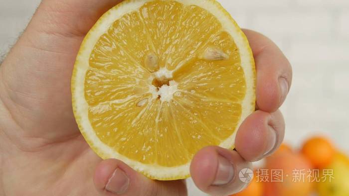 用手从新鲜柠檬水果中榨汁的特写图片