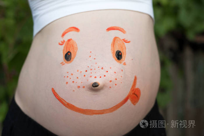 一个有着彩色笑脸的孕妇的腹部绿色背景