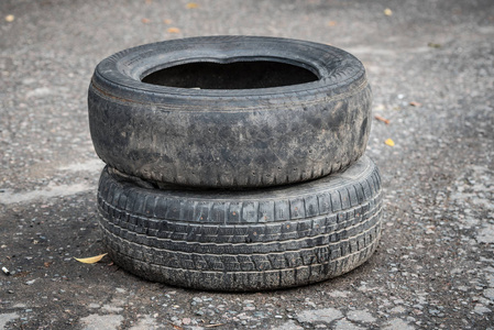 脏轮旧的脏汽车轮胎在破裂的沥青上.特写照片