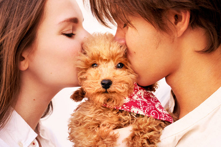 这对夫妇抱着可爱的小狗,亲吻并拥抱它.照片