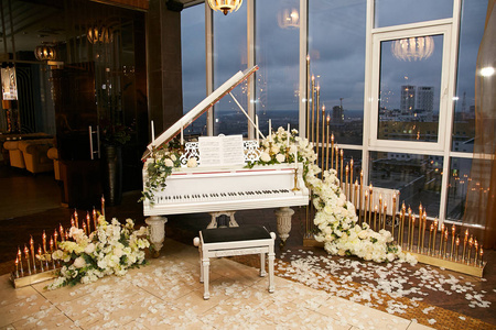 一架漂亮的白色钢琴,上面装饰着天然的花朵,还有一个装饰着旧灯的花环