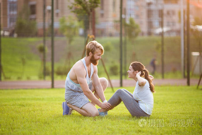 仰卧起坐健身夫妇在草地上锻炼仰卧起坐适合进行交叉训练的人和教练一