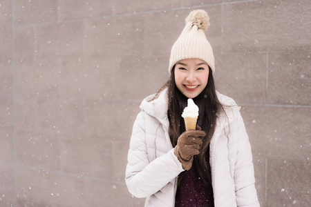 美丽的年轻亚洲女人微笑着,开心地吃着雪糕照片