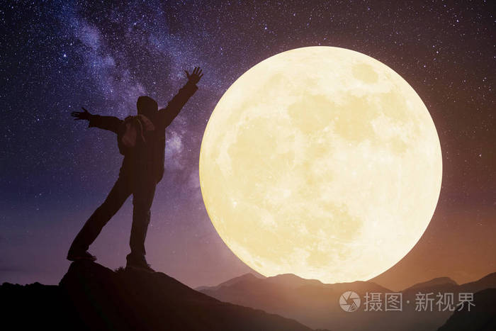 年轻人站在山上看着月亮庆祝一下中a