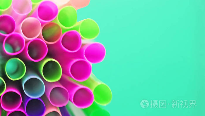 蓝色背景下的许多彩色塑料鸡尾酒管不同寻常的俯视图。喝着明亮霓虹色的 