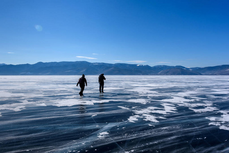 冰天雪地,两个人的剪影在美丽的山上行走.自然背景照片