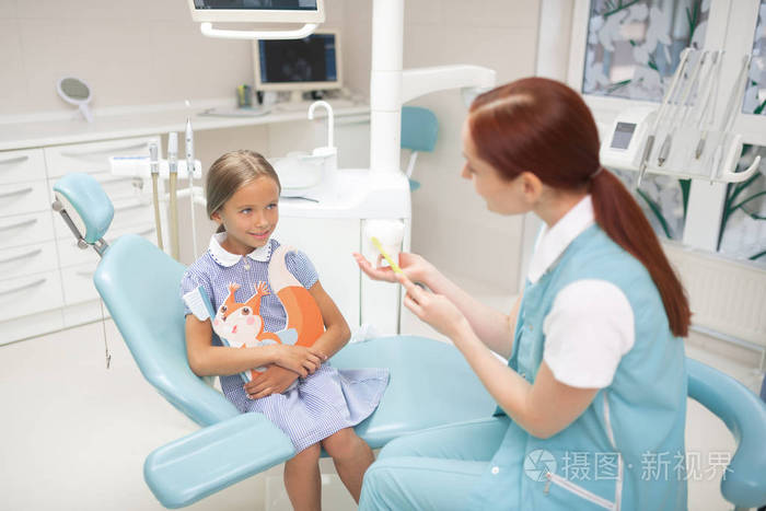 女孩看着牙医讲述牙齿的俯视图