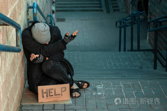 一个无家可归的人在街上用求助标志乞讨.