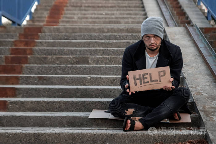 一个无家可归的人在街上用求助标志乞讨无家可归者瘾君子贫穷绝望的