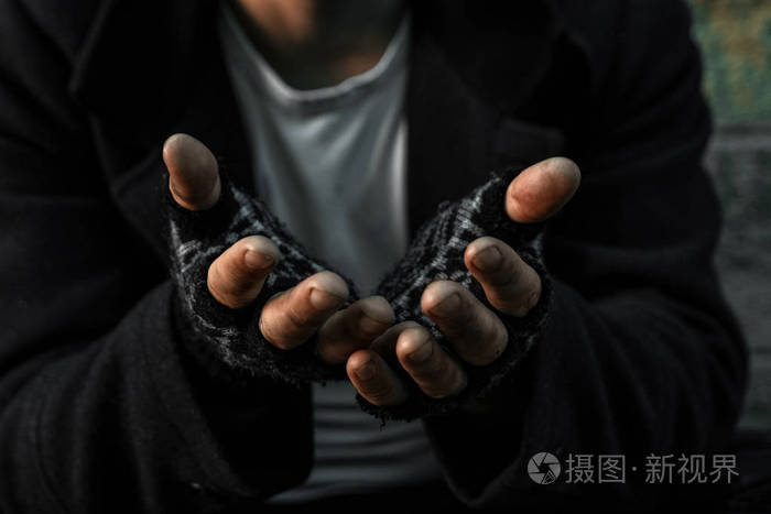 双手合拢坐在肮脏的贫民窟里乞求你帮助的可怜的老人或乞丐贫困或饥饿
