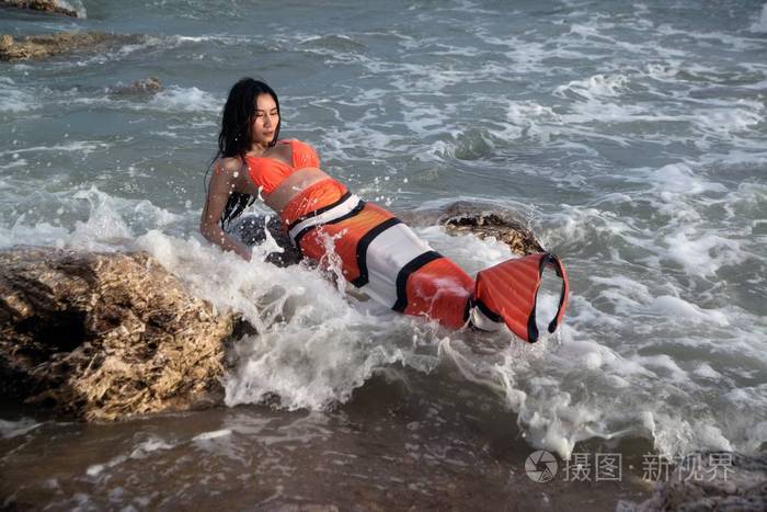 美丽的亚洲女子比基尼和美人鱼礼服在海滩上的乐趣