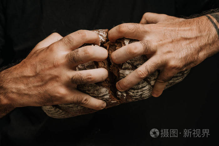 男性手掰着刚烤好的面包特写