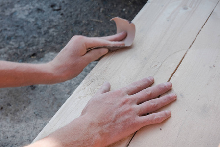 用砂纸打磨木头.一个人擦树.用砂纸.制作木制品.使木板光滑.照片