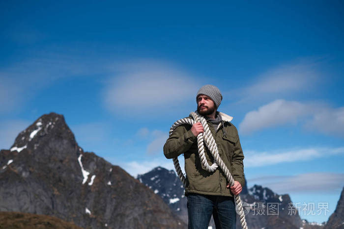 在群山蓝天的背景下肩上扛着绳子的野蛮人复制空间可用作横幅