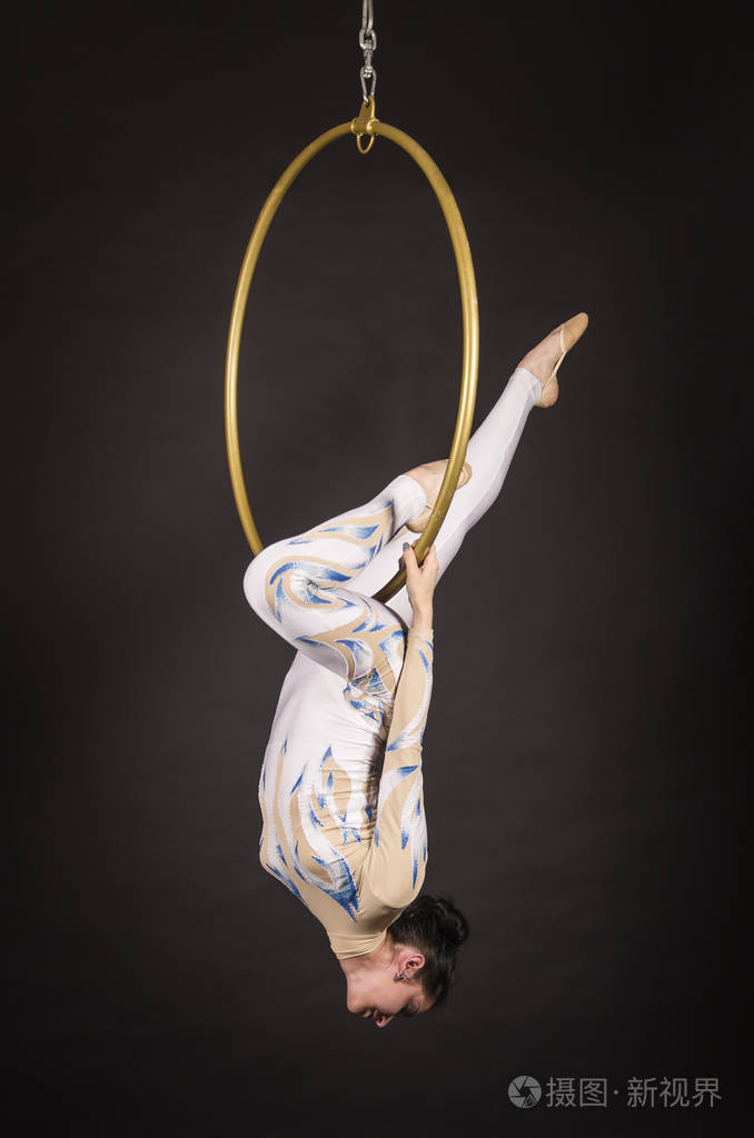 一个身材修长黑发的女孩一个穿着白蓝相间套装的空中杂技演员在空中