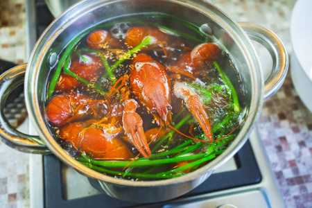 锅里煮小龙虾,欧芹绿色,俯视图.甲壳动物在水中用香料和草药烹调照片