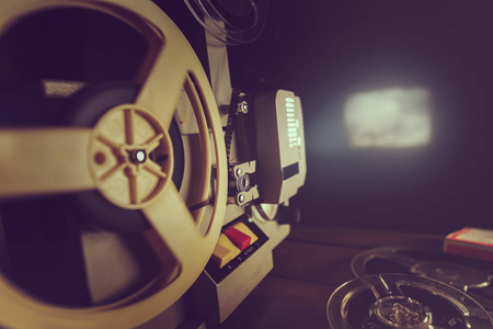 黑暗中的光亮复古8毫米电影放映机在黑暗中在墙上播放旧电影照片