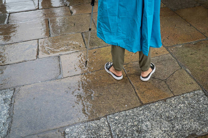 雨天穿着蓝色油布和凉鞋的面目全非的人