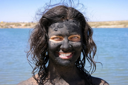 泥巴人微笑的女人脸上沾满了愈合的泥巴.照片