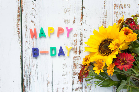 生日快乐贺卡,鲜花花束,向日葵,在浅色木质背景上带有明亮的文字祝贺.