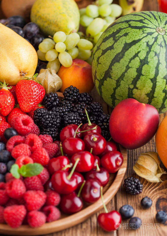 新鲜的有机夏季浆果混合在木制托盘和异国情调的水果木质背景覆盆子