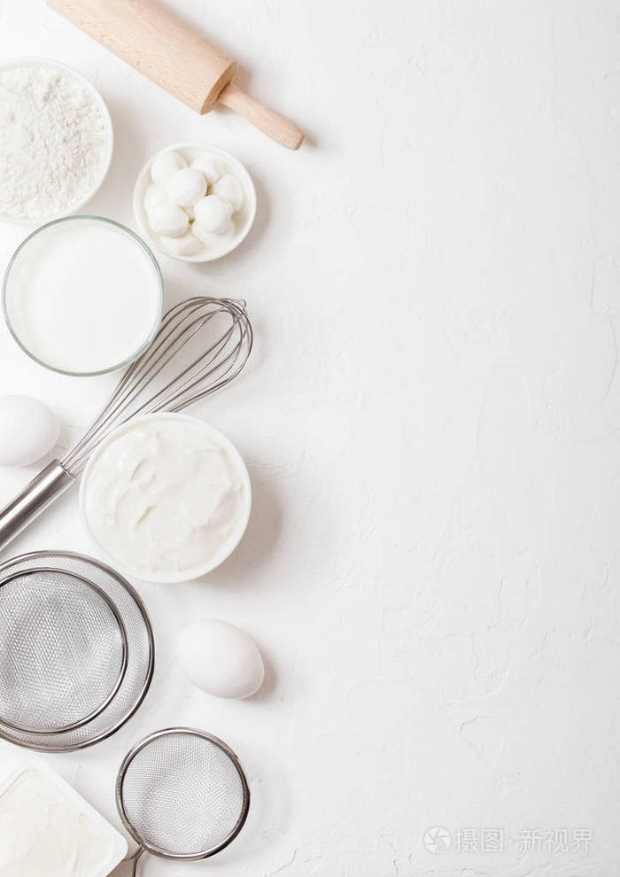 白色桌面背景上的新鲜乳制品一杯牛奶一碗面粉酸奶油干酪和鸡蛋钢制