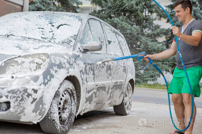 夏天一个男人在户外的自助水槽里洗车