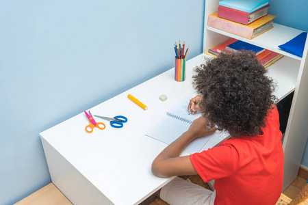 黑人日日本打扮黑人男孩在笔记本上写字.孩子坐在书桌前做作业.